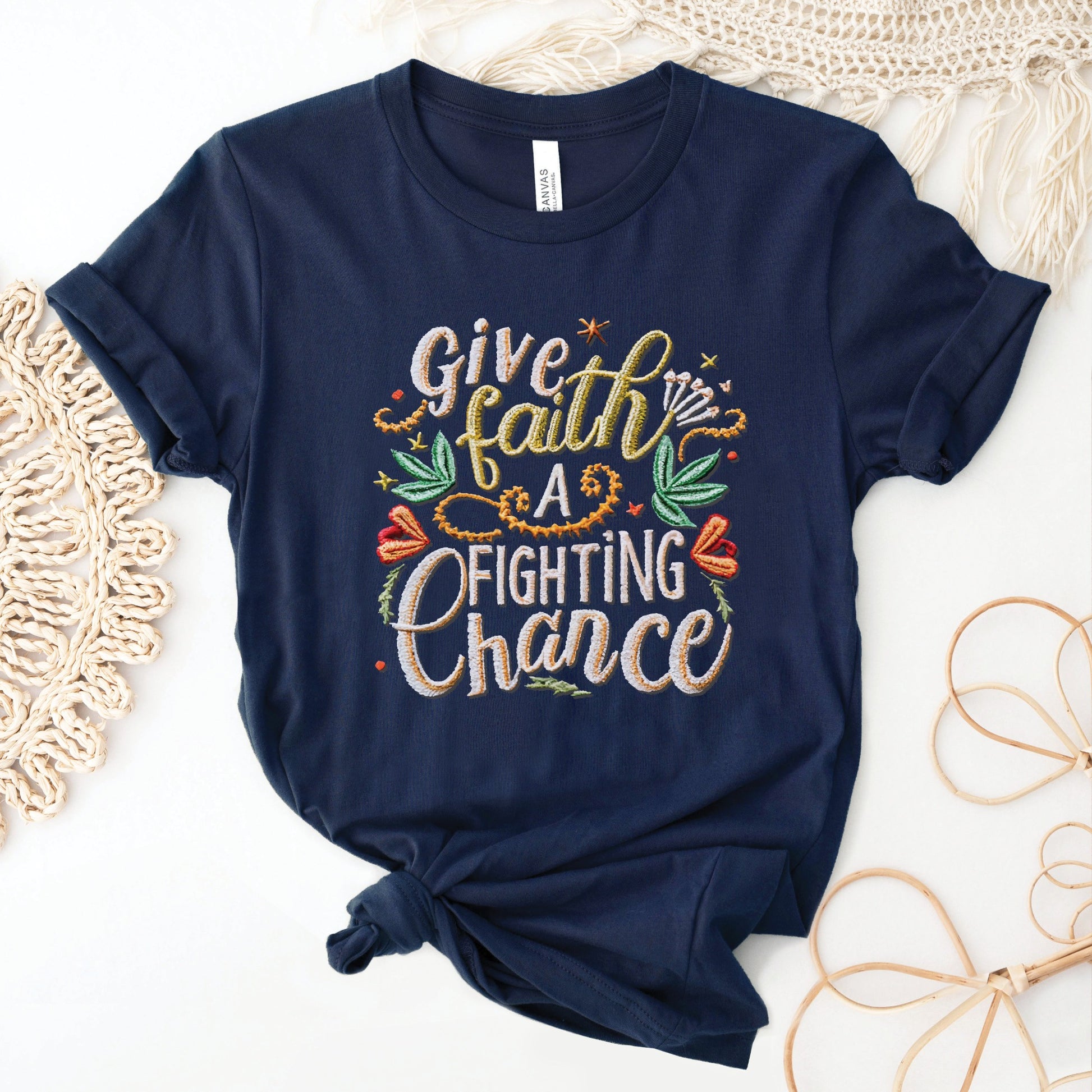 Navy blue soft t-shirt with printed embroidery font Christian Bible verse quote that says, "Give Faith A Fighting Chance" with flower and leaf graphics, faith-based t-shirt designed for women