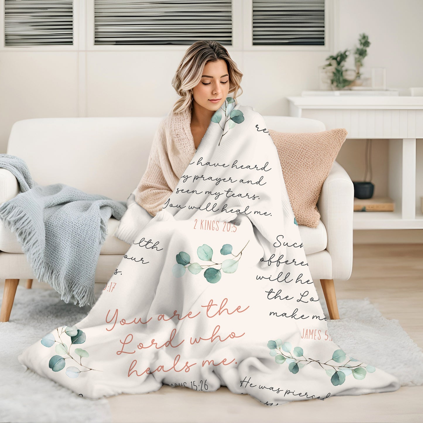 Young woman wrapped up in a cozy silky soft luxurious ivory, dusty rose, green and white minky blanket with 8 Christian healing scripture bible verses to heal and protect with sage green watercolor eucalyptus branches