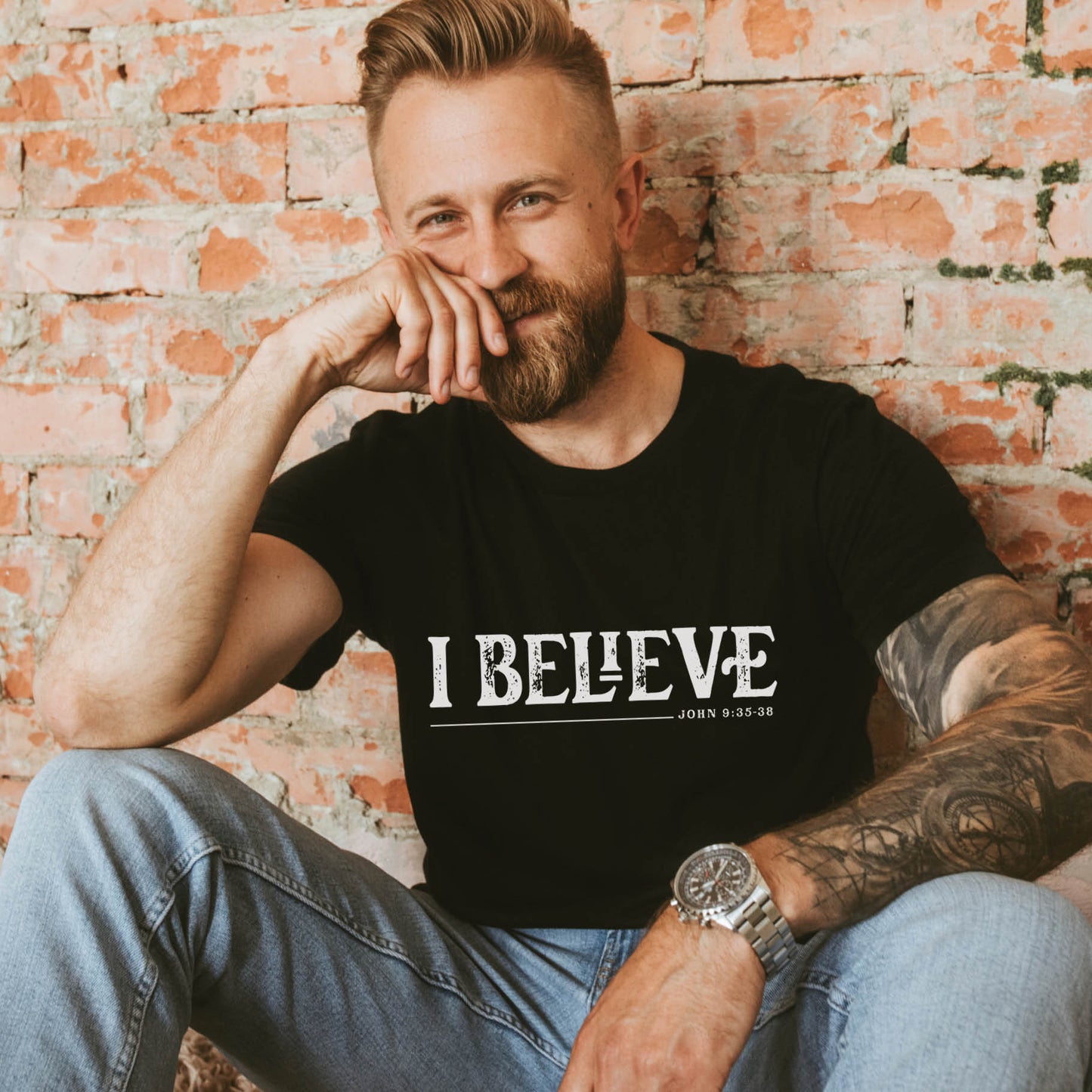 Modern man believer with a beard and tattoos wearing a black I BELIEVE John 9:35-38 bible verse faith statement Men's Christian black t-shirt, "I was blind and now I see" scripture