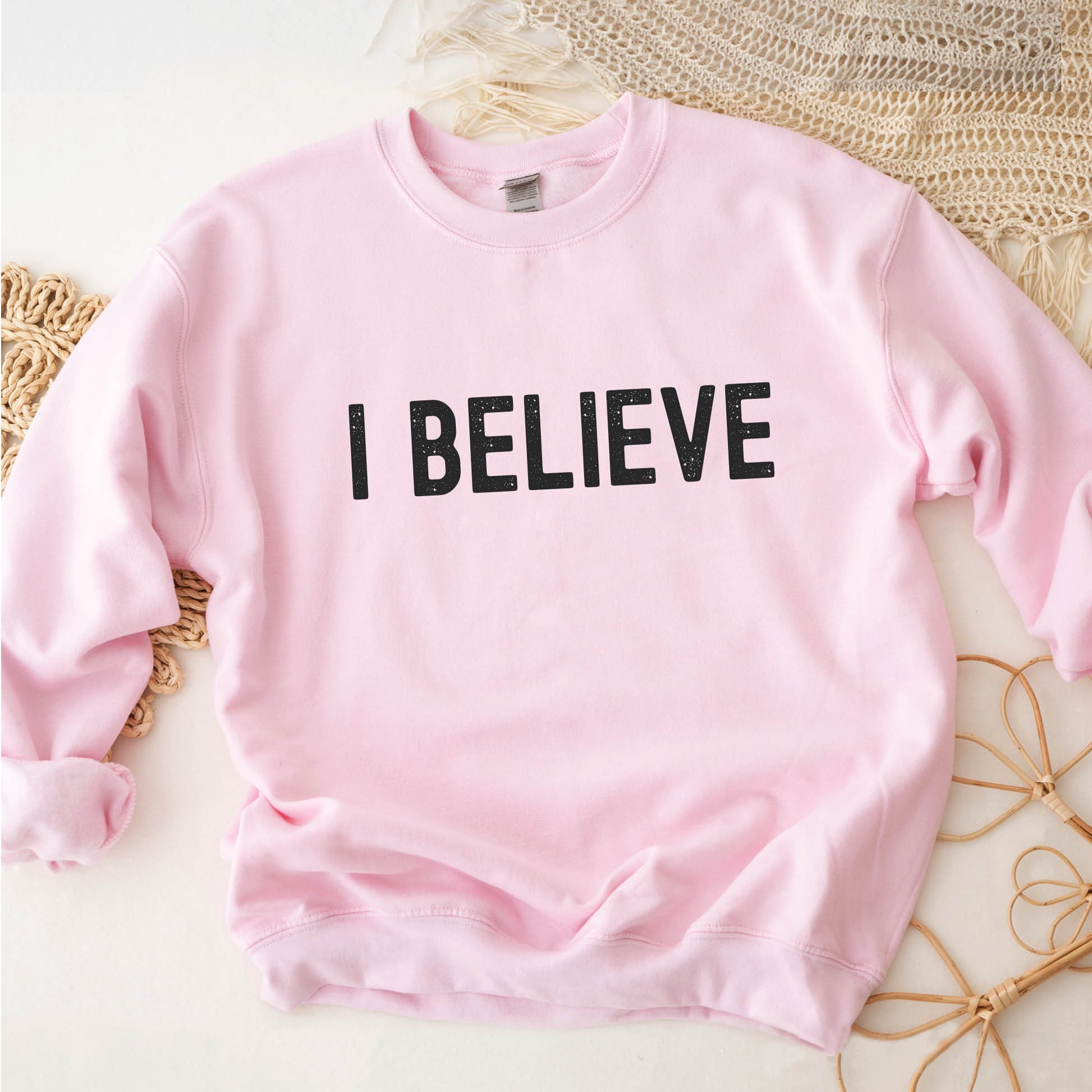 I Believe Christian aesthetic Jesus believer matte black simple distressed typography design printed on cozy light pink unisex crewneck sweatshirt, created for men & women