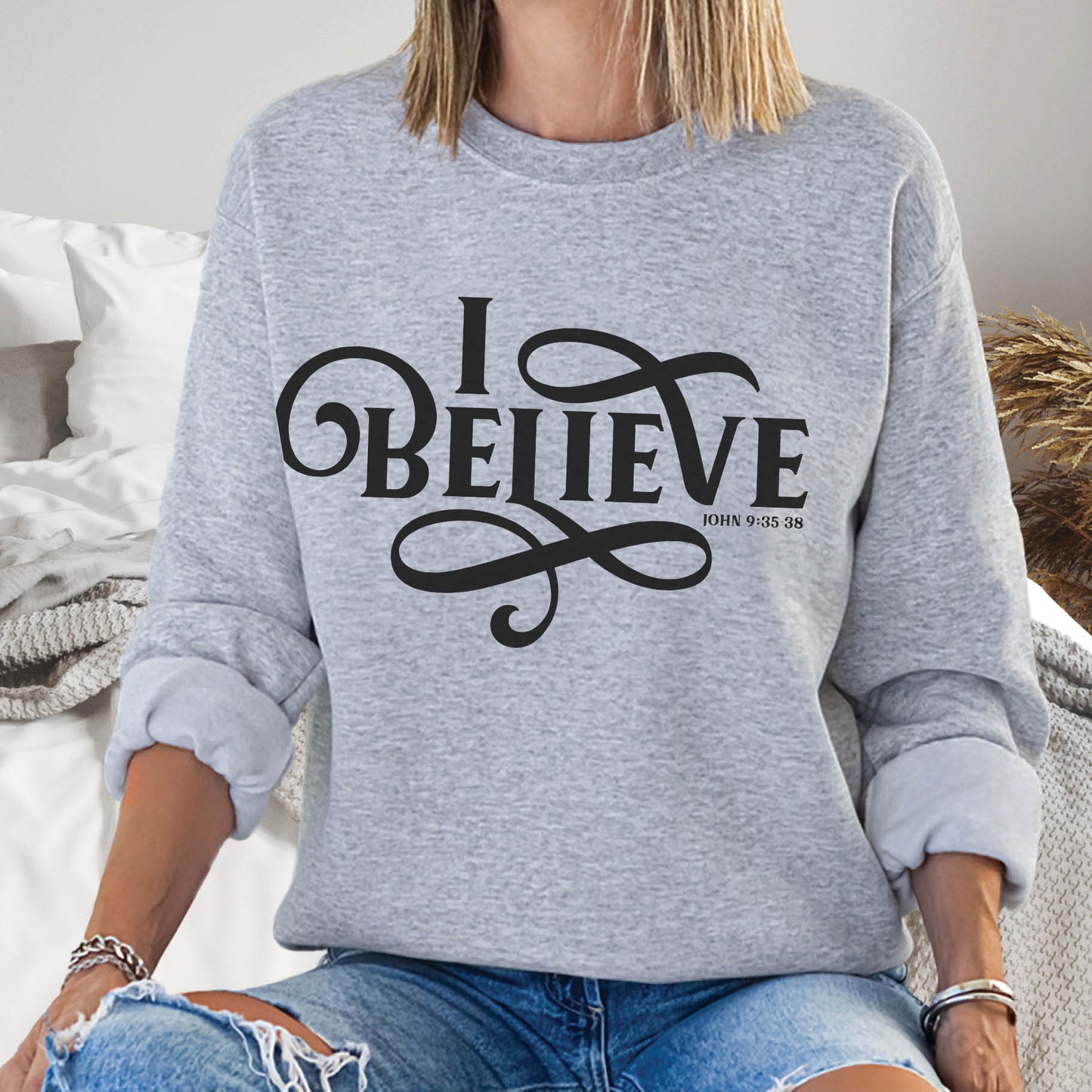 Young woman wearing a heather gray I BELIEVE John 9:35-38 bible verse women's Christian unisex cozy sweatshirt, designed for faith-filled Jesus believers in size small, medium, large, XL, 2XL, 3XL, 4XL