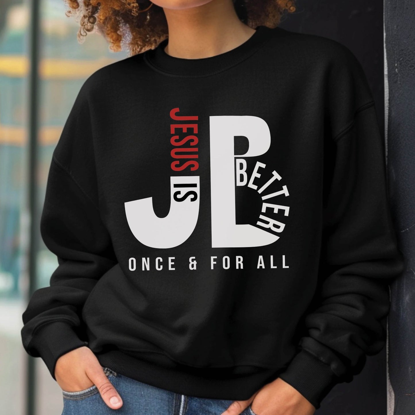 Cozy "JB" typography "Jesus is Better Once and For All" design in white and red letters, based on the Christian bible book of Hebrews, printed on a black color Unisex crewneck sweatshirt, created for faith-based men and women