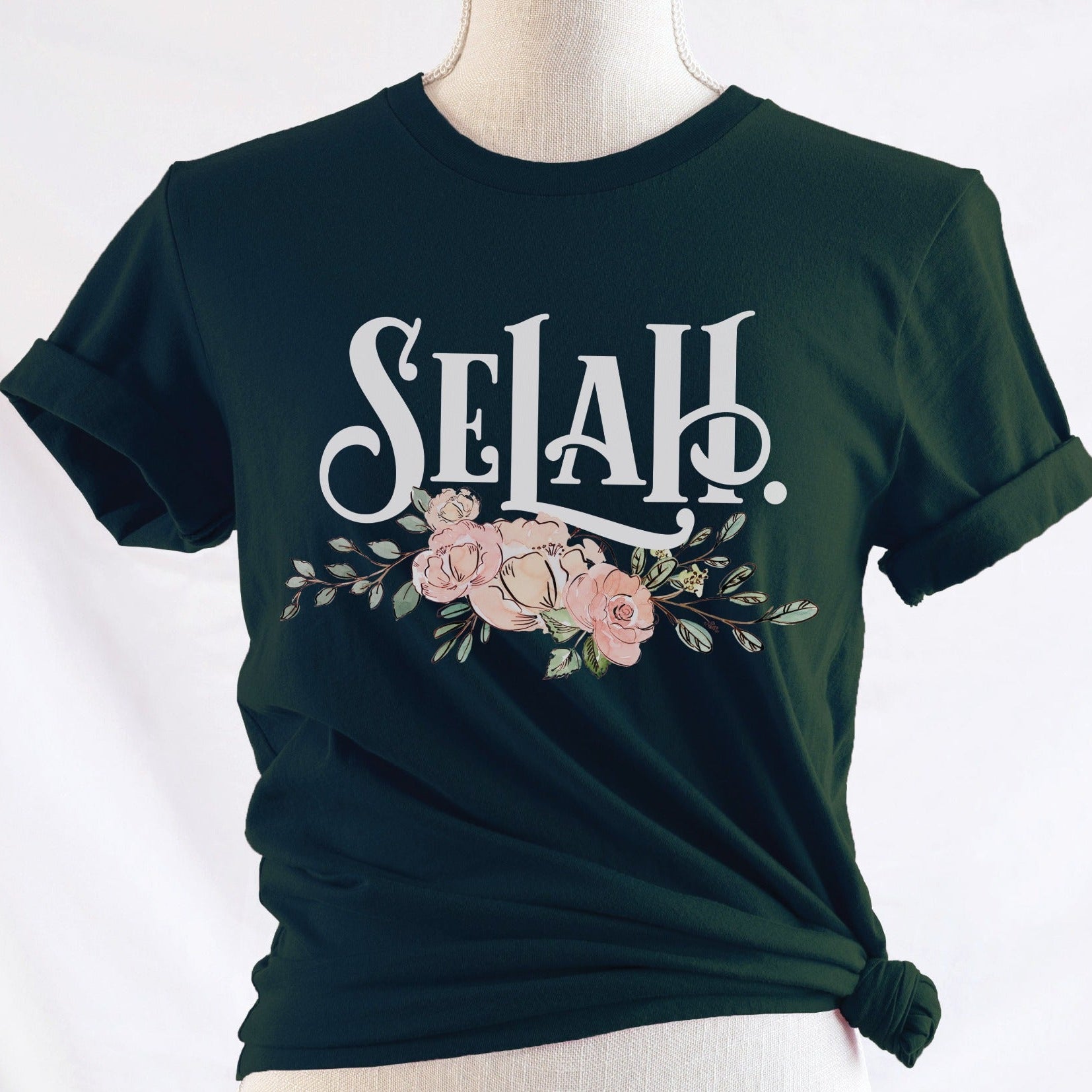 SELAH Psalm bible verse watercolor floral Christian aesthetic design printed in white, peach, and blush pink on soft dark forest green t-shirt for women
