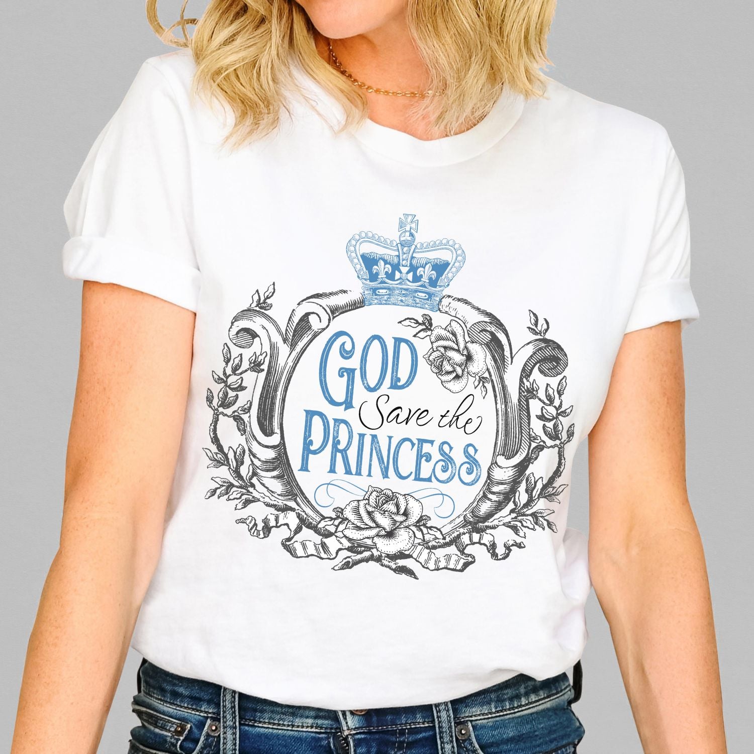 Woman wearing a soft white vintage British Royal Family women's unisex t-shirt that says "God Save the Princess"  with Blue crown, roses, and baroque filigree frame design, created as a reminder to pray for the United Kingdom Princess of Wales, Kate Middleton in her battle with cancer