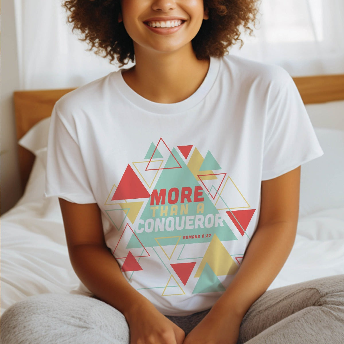 Young woman wearing a white "More Than A Conqueror" Romans 8:37 bible verse scripture unisex faith-based Christian Bella Canvas 3001 t-shirt, with bright and colorful geometric triangles pattern, made in the USA for Men and Women Jesus believers