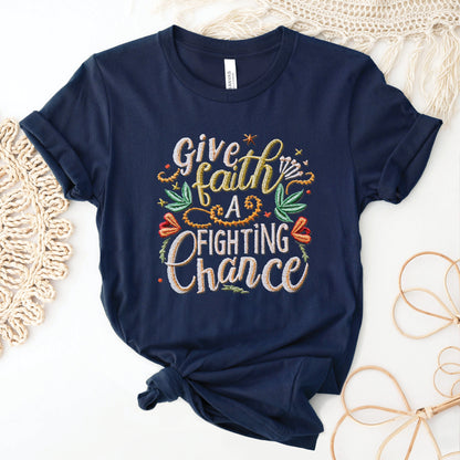 Navy blue soft t-shirt with printed embroidery font Christian Bible verse quote that says, "Give Faith A Fighting Chance" with flower and leaf graphics, faith-based t-shirt designed for women