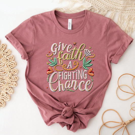 Trendy mauve dusty rose t-shirt with printed embroidery font Christian Bible verse quote that says, "Give Faith A Fighting Chance" with flower and leaf graphics, faith-based t-shirt designed for women