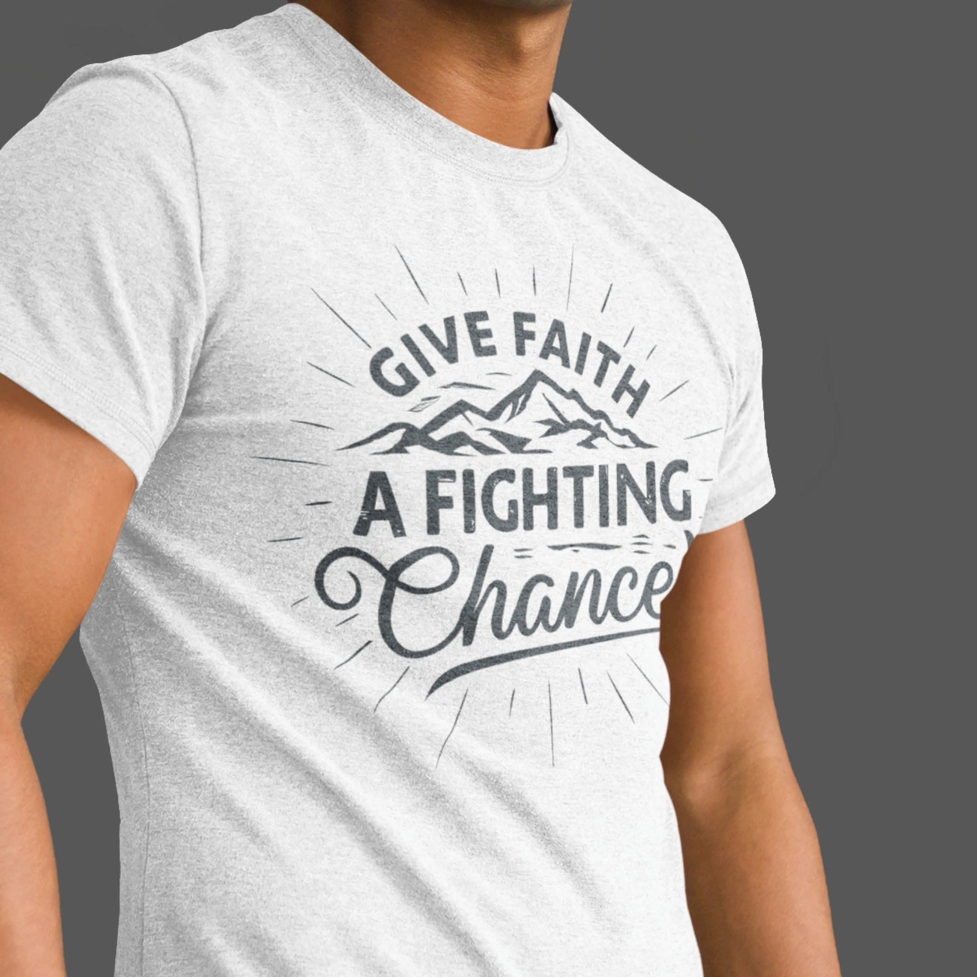 Young man wearing a Heather Gray Unisex Tee with Christian Bible verse quote that says, "Give Faith A Fighting Chance" in charcoal gray with retro sunburst and mountain graphics, t-shirt designed for faith-based men and women