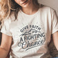 Woman wearing a Soft Cream Unisex Tee with Christian Bible verse quote that says, "Give Faith A Fighting Chance" in charcoal gray with retro sunburst and mountain graphics, t-shirt designed for faith-based men and women