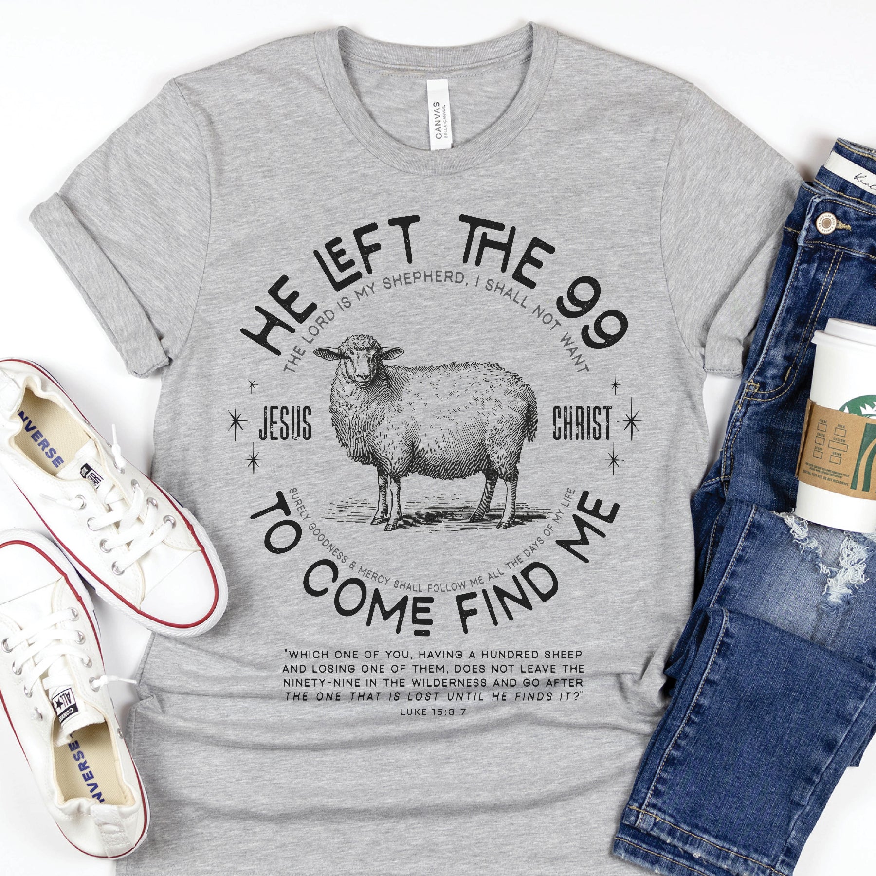 Gray Christian unisex t-shirt laying on a on a white background with He Left the 99 to Come Find Me Jesus Christ Luke 15 bible verse and vintage sheep illustration graphic and distressed text printed in black