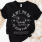 Black Christian unisex t-shirt laying on woven raffia mats with He Left the 99 to Come Find Me Jesus Christ Luke 15 bible verse and vintage sheep illustration graphic and distressed text printed in white