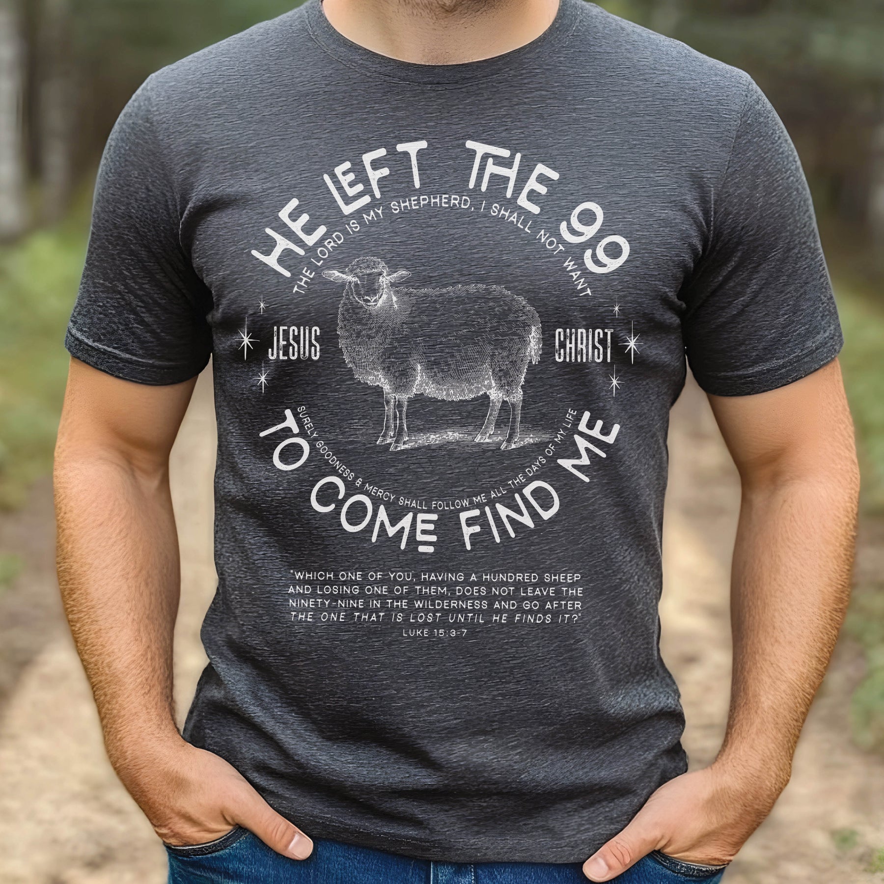 Man wearing a heather dark gray Christian unisex t-shirt with He Left the 99 to Come Find Me Jesus Christ Luke 15 bible verse and vintage sheep illustration graphic and distressed text printed in white