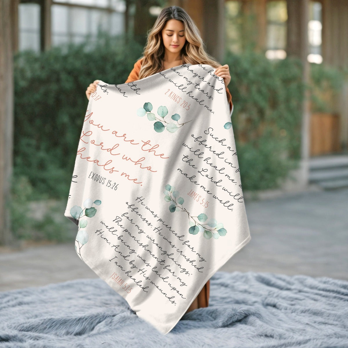 Woman holding up an silky soft luxurious ivory, dusty rose, green and white minky blanket with 8 Christian healing scripture bible verses to heal and protect with sage green watercolor eucalyptus branches