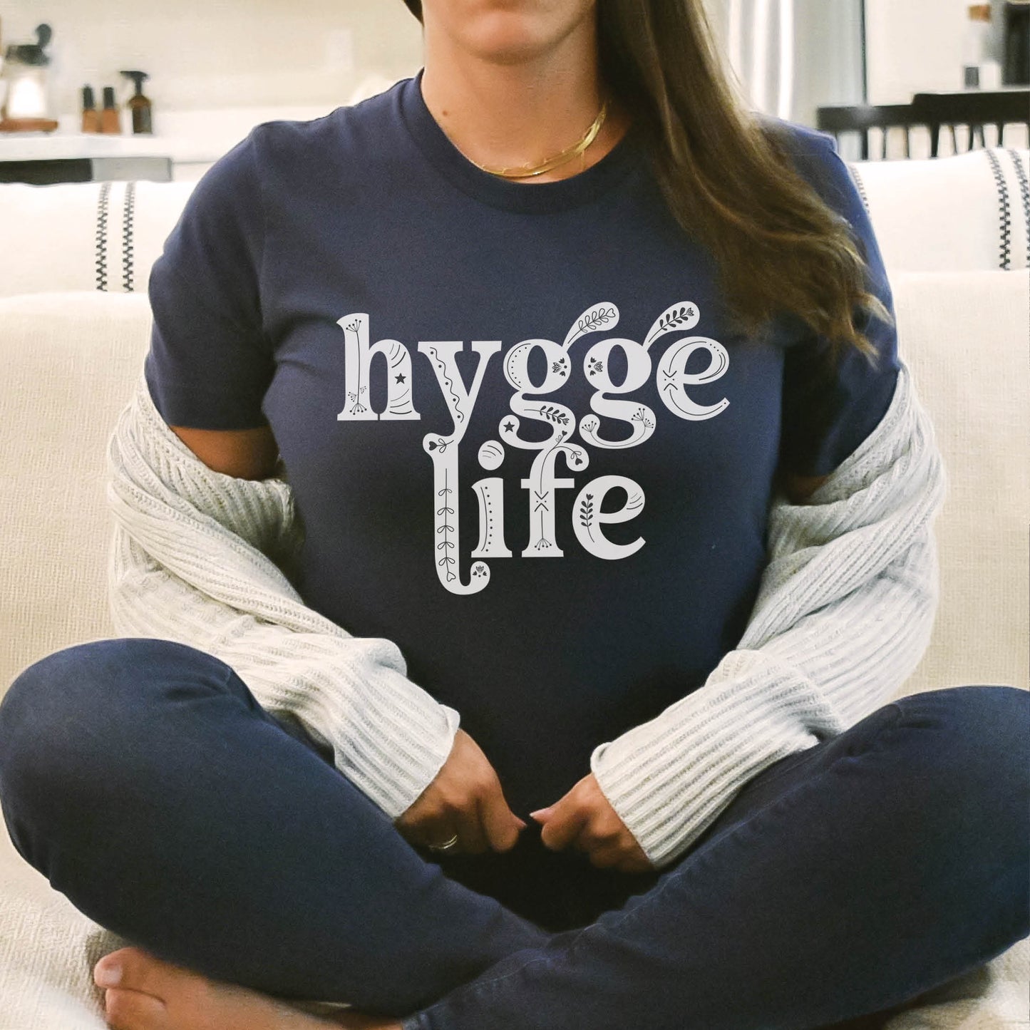 Coziness vibes woman wearing a warm sweater and Navy Blue "Hygge Life" quote Holy Hygge Women's unisex Christian t-shirt with Scandinavian floral and heart art for the cozy fall and winter season