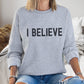 Young woman wearing an "I Believe" Christian aesthetic Jesus believer matte black simple distressed typography design printed on cozy heather sport gray unisex crewneck sweatshirt, created for men & women