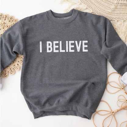 I Believe Christian aesthetic Jesus believer simple distressed white typography design printed on cozy heather dark gray unisex crewneck sweatshirt, created for men & women