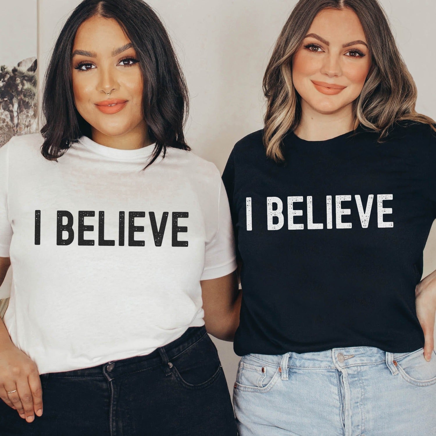 2 young diverse light and dark skinned women wearing I BELIEVE Christian aesthetic faith-based bold statement distressed typography t-shirt design printed in white on soft black and white unisex fit t-shirt, designed for men & women believers