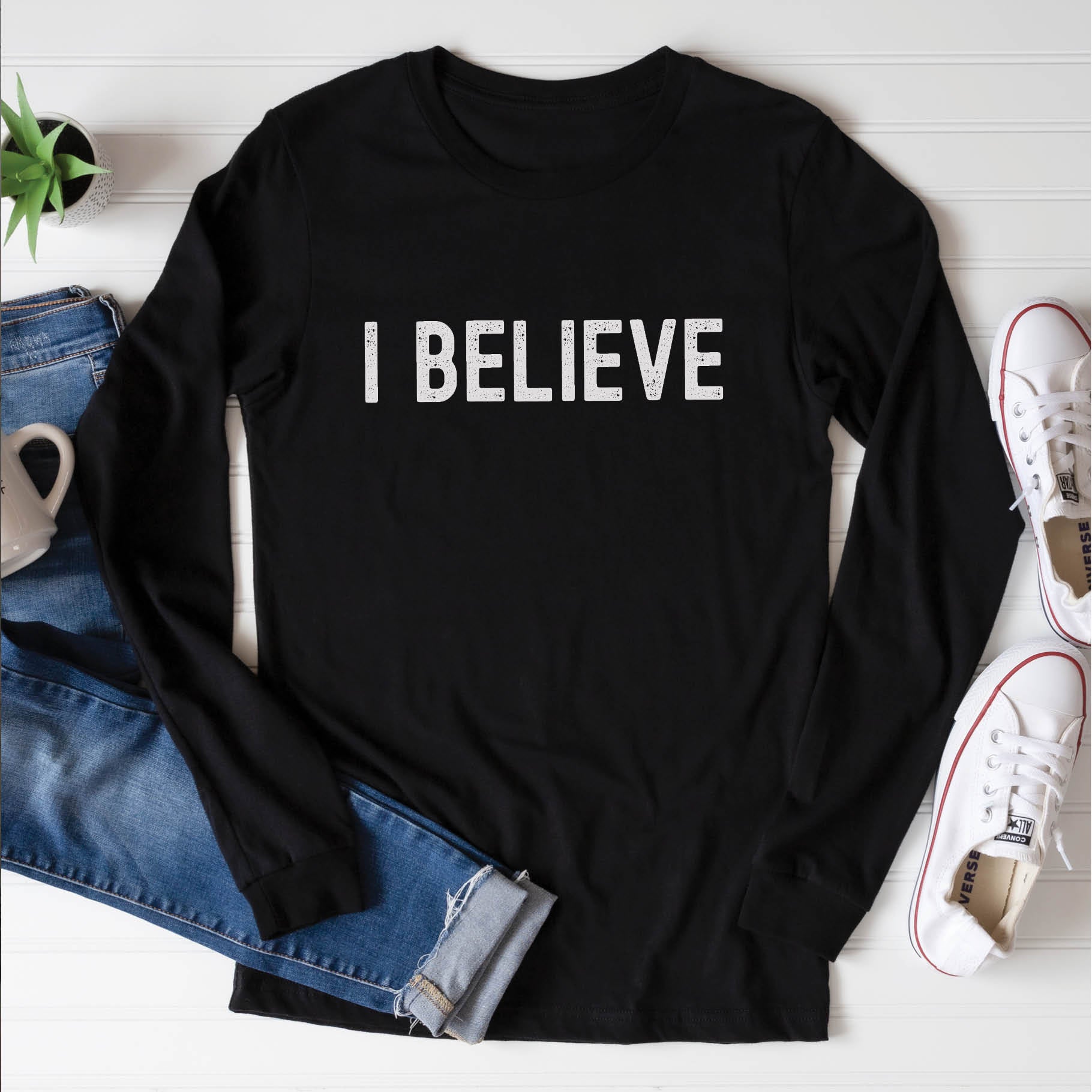 Black cozy long sleeve t-shirt with a bold faith-based statement "I BELIEVE" distressed typography design printed in white, created for Christian men and women Jesus believers