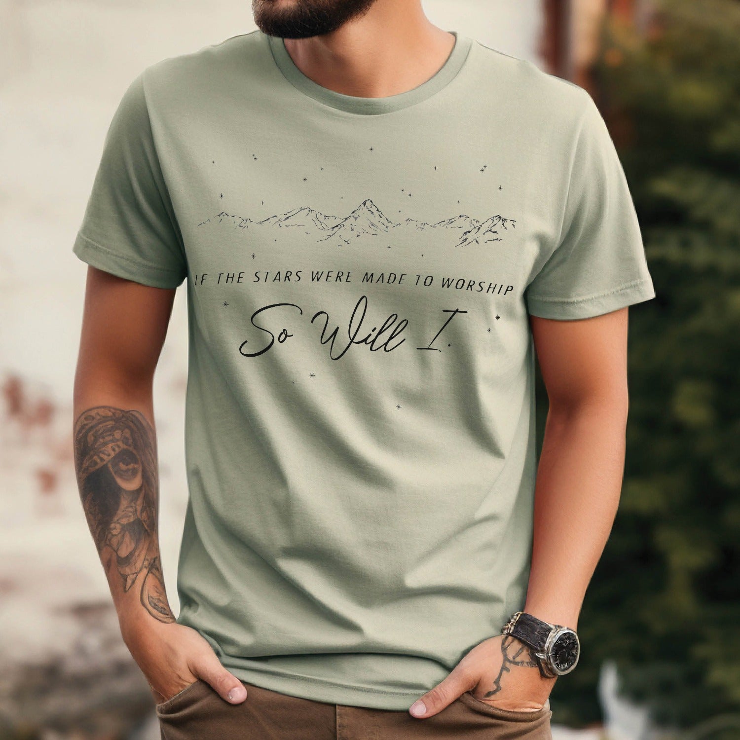 Christian man wearing a Bay sage green color garment-dyed unisex Comfort Colors 1717 t-shirt with black mountain range and starry sky that says this faith-based bible verse quote, "If the Stars Were Made to Worship So Will I", created for men and women Kingdom believers
