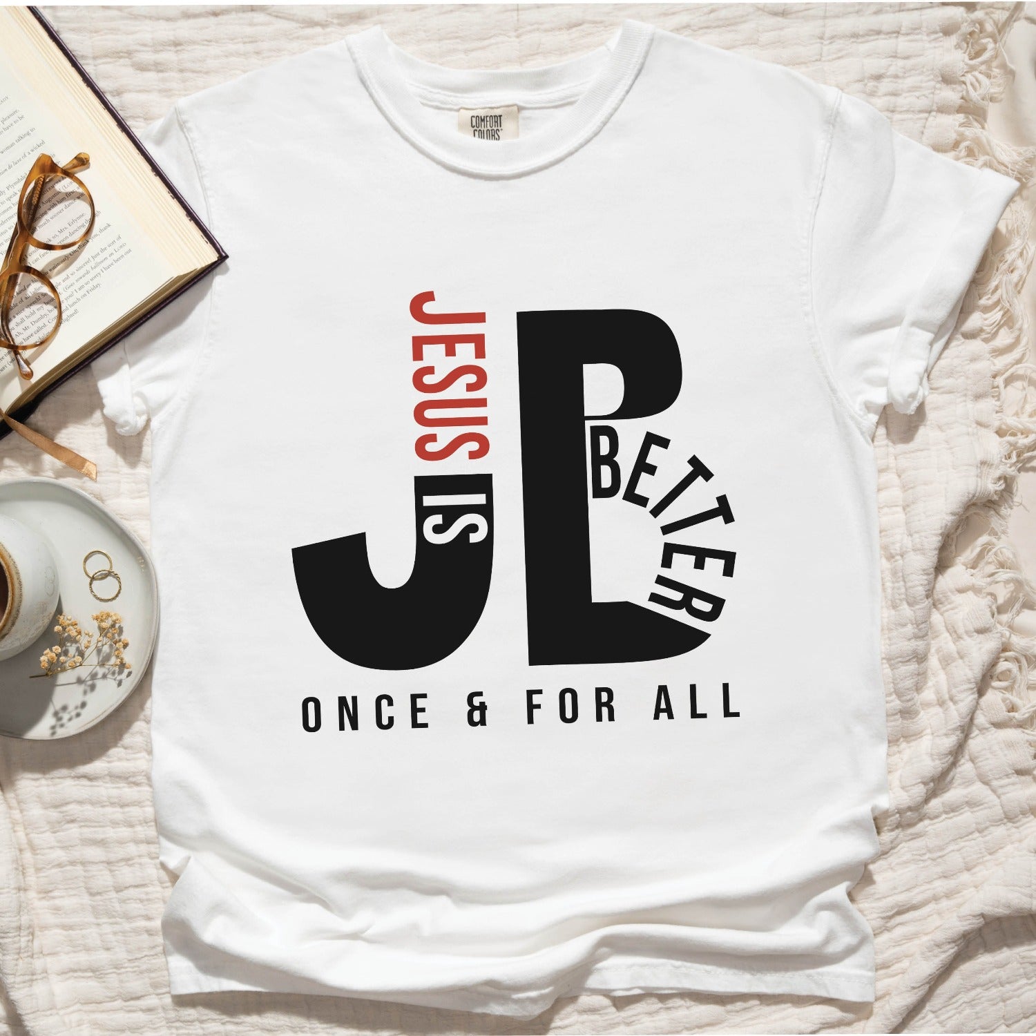 "JB" typography "Jesus is Better Once and For All" design in black and red Christian book of Hebrews, printed on a white color Unisex Comfort Colors C1717 t-shirt, with Jesus in red letters, created for faith-based women and men