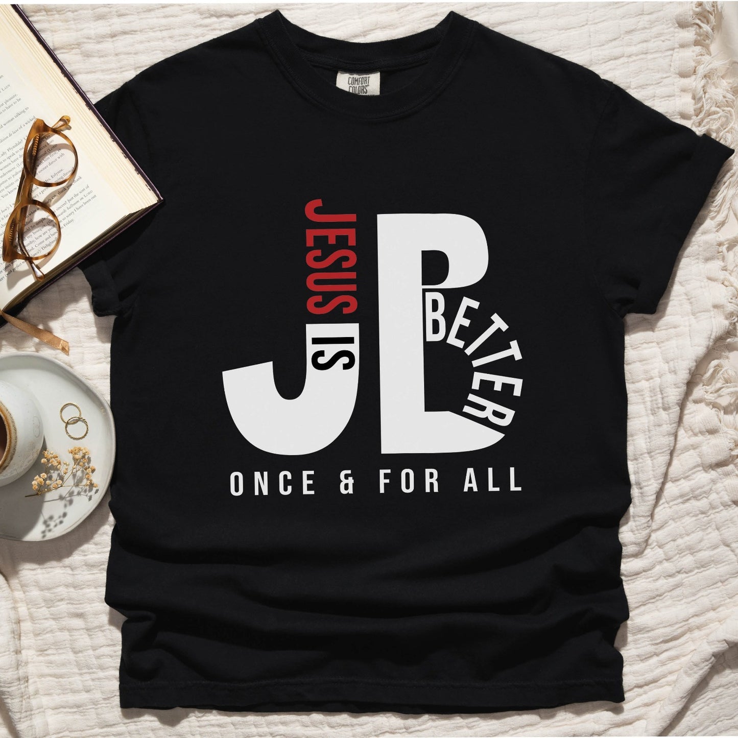 "JB" typography "Jesus is Better Once and For All" design in white and red, Christian, based on the bible book of Hebrews, printed on a black color Unisex Comfort Colors C1717 t-shirt, with Jesus in red letters, created for faith-based women and men