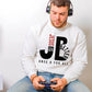 Young man wearing a cozy "JB" typography "Jesus is Better Once and For All" design in black and red letters, based on the Christian bible book of Hebrews, printed on a white color Unisex crewneck sweatshirt, created for faith-based men and women, great father's day gift for Dad