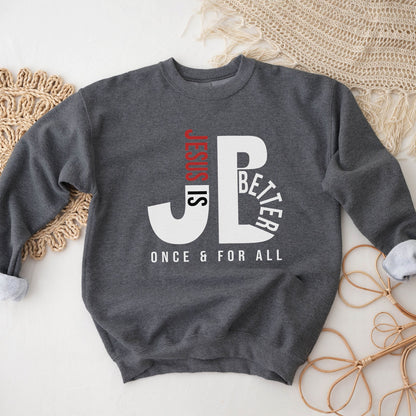 Cozy "JB" typography "Jesus is Better Once and For All" design in white and red letters, based on the Christian bible book of Hebrews, printed on a heather dark gray color Unisex crewneck sweatshirt, created for faith-based men and women