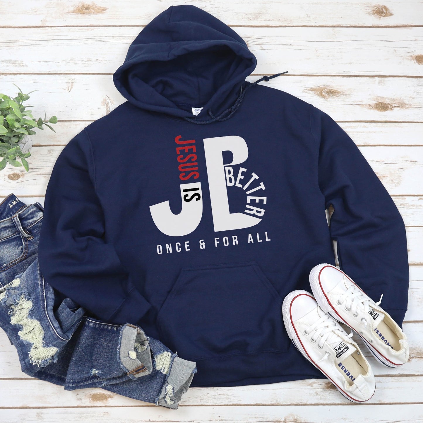 "JB" typography "Jesus is Better Once and For All" design in white and red letters, based on the Christian bible book of Hebrews, printed on a navy blue color cozy unisex hoodie, created for faith-based men and women, great father's day gift for Dad