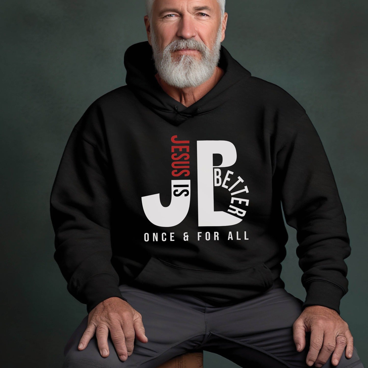 Man like a dad or grandpa wearing a cozy "JB" typography "Jesus is Better Once and For All" design in white and red letters, based on the Christian bible book of Hebrews, printed on a black color unisex hoodie, created for faith-based men and women, great father's day gift for Dad