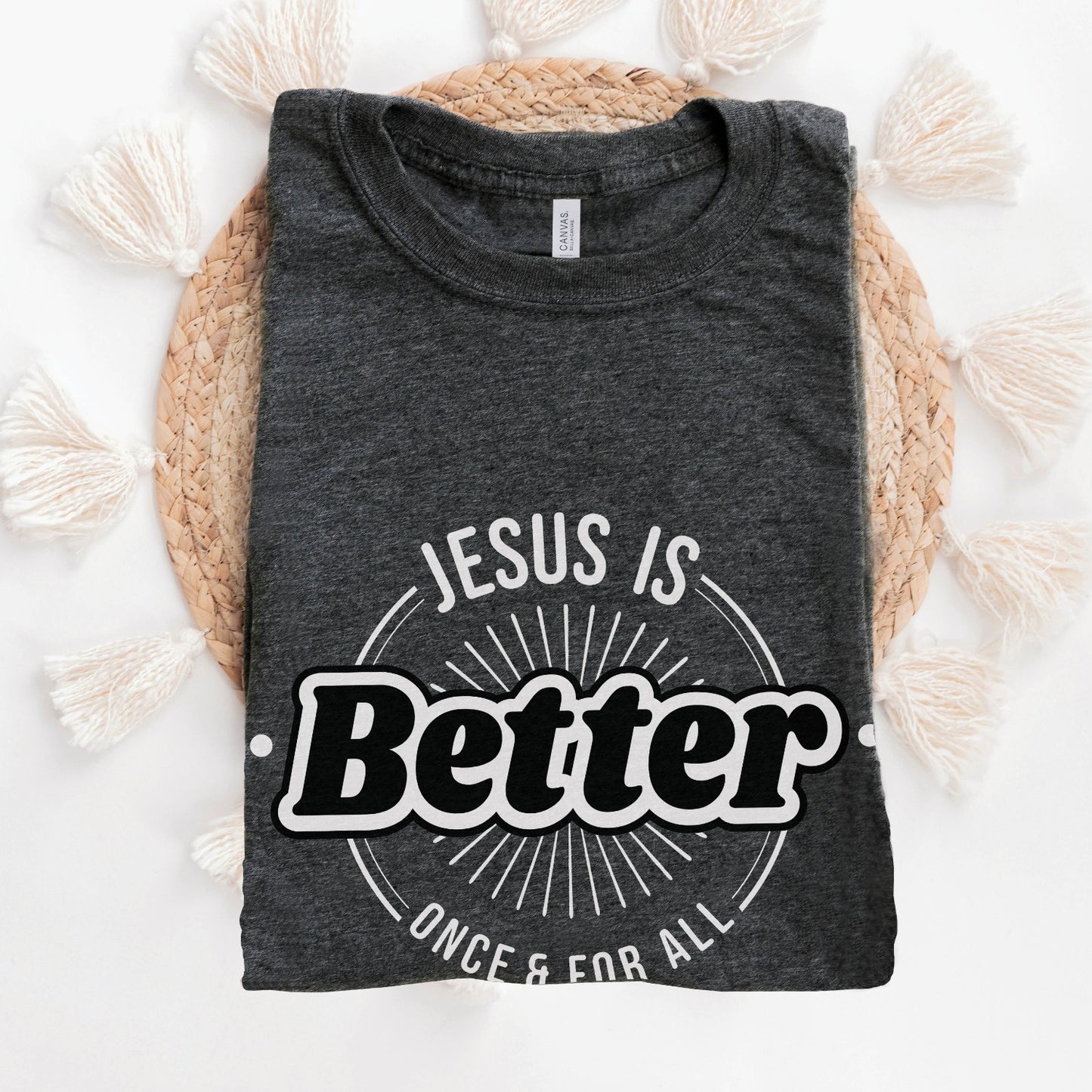 Folded Heather Dark Gray "Jesus Is Better - Once & For All" bible book of Hebrews faith-based Christian unisex t-shirt for women with a bold white and black sunburst logo style design