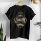 Black Christian faith-based unisex t-shirt featuring a gold ornamental blackletter-style frame design with the text 'Jehovah Jireh The Lord My Provider' and 'Genesis 22:14' Bible verse, elegant and inspirational religious apparel for men and women