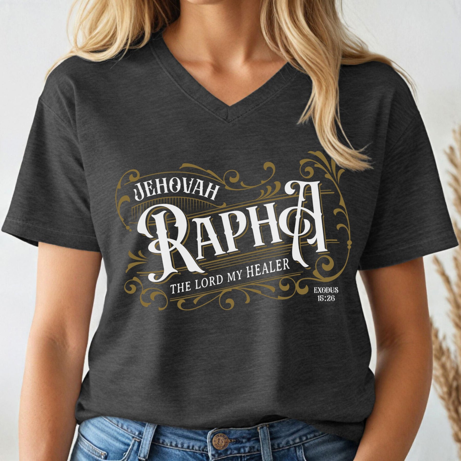 Dark heather gray V-neck women's Christian t-shirt with 'Jehovah Rapha, The Lord My Healer, Exodus 18:26 bible verse' vintage blackletter style design worn by a woman