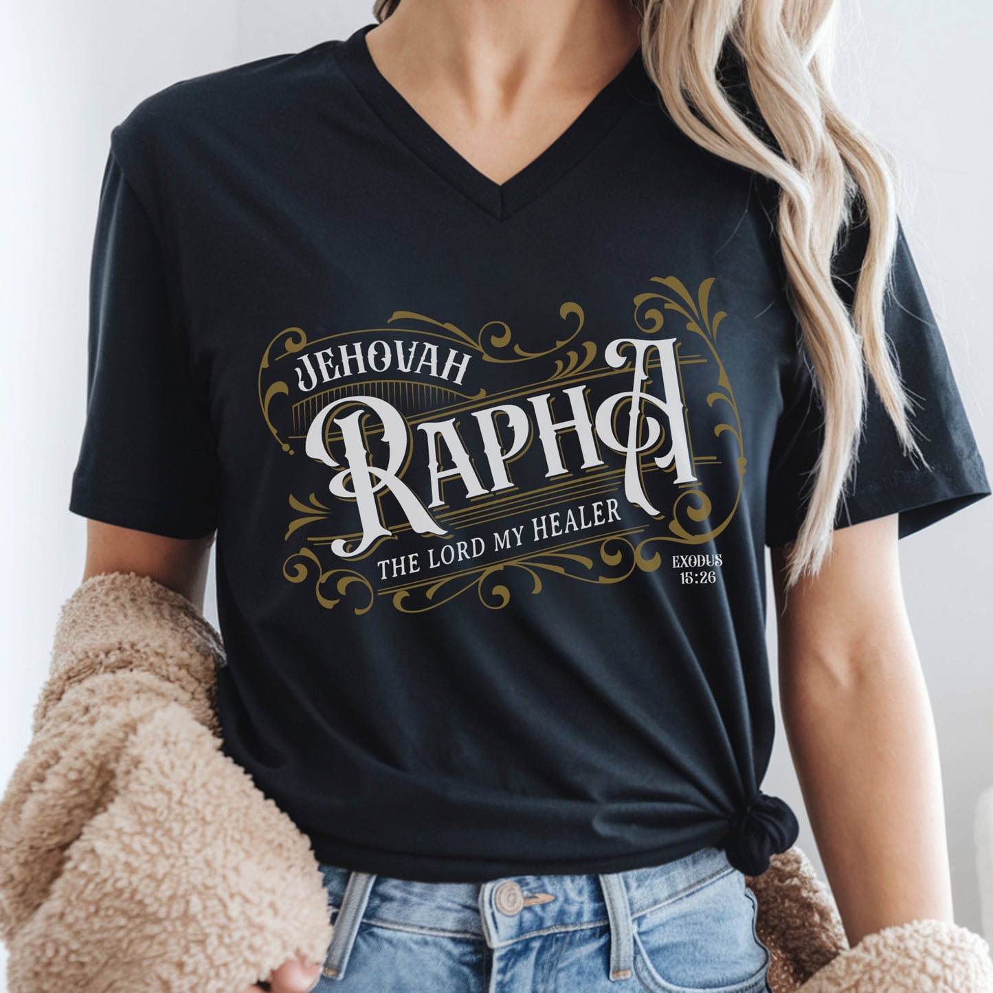 Black V-neck women's Christian t-shirt with 'Jehovah Rapha, The Lord My Healer, Exodus 18:26 bible verse' vintage blackletter style design worn by a woman.