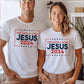 Patriotic man and woman wearing white President election vote unisex Christian t-shirts with "Jesus 2024 - Keep America Saved" and stars printed in bold red, white, and blue fonts, made in the USA, made for men and women God & Country Patriots