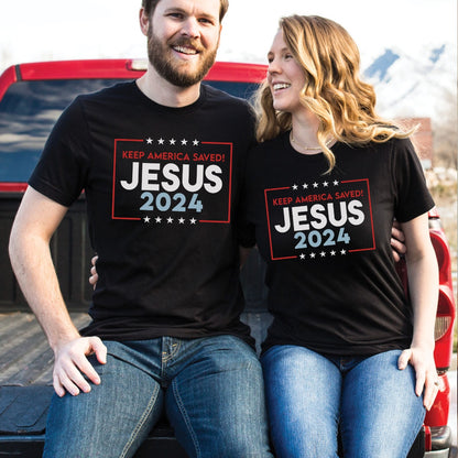 Happy Patriotic man and woman wearing black President election vote unisex Christian t-shirts with "Jesus 2024 - Keep America Saved" and stars printed in bold red, white, and blue fonts, made in the USA, made for men and women God & Country Patriots