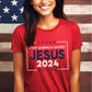 Patriotic young woman wearing white President election vote unisex Christian t-shirt with "Jesus 2024 - Keep America Saved" and stars printed in bold red, white, and blue fonts, made in the USA, made for men and women God & Country Patriots