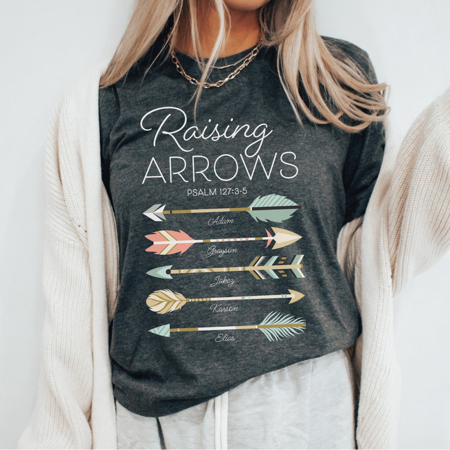 Christian mom wearing a unisex dark heather gray t-shirt with 'Raising Arrows' Psalm 127:3-5 design with five personalized names under each arrow on a white background