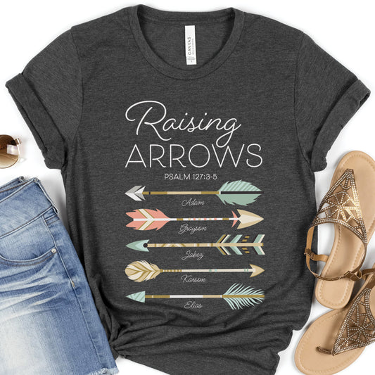 Dark heather gray t-shirt with 'Raising Arrows' design with area for 5 personalized names under each arrow and accessories on a white background