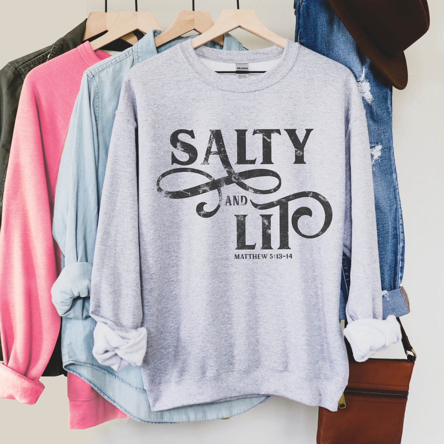 Faith-based "Salty And Lit Matthew 5:13-14" bible verse funny Christian aesthetic unisex crewneck sweatshirt with distressed swirl typography design printed in charcoal gray on cozy heather sport gray sweater for women