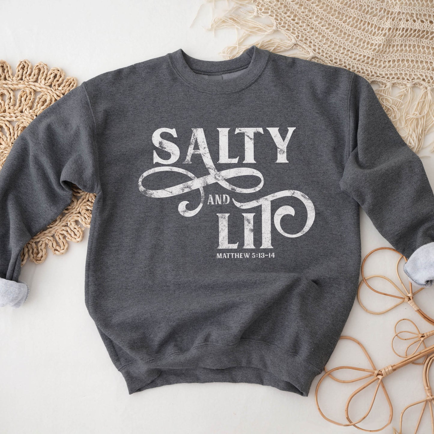 Salty And Lit Matthew 5:13-14 bible verse funny Christian aesthetic unisex crewneck sweatshirt with distressed swirl typography design printed in white on cozy heather dark gray sweater for women