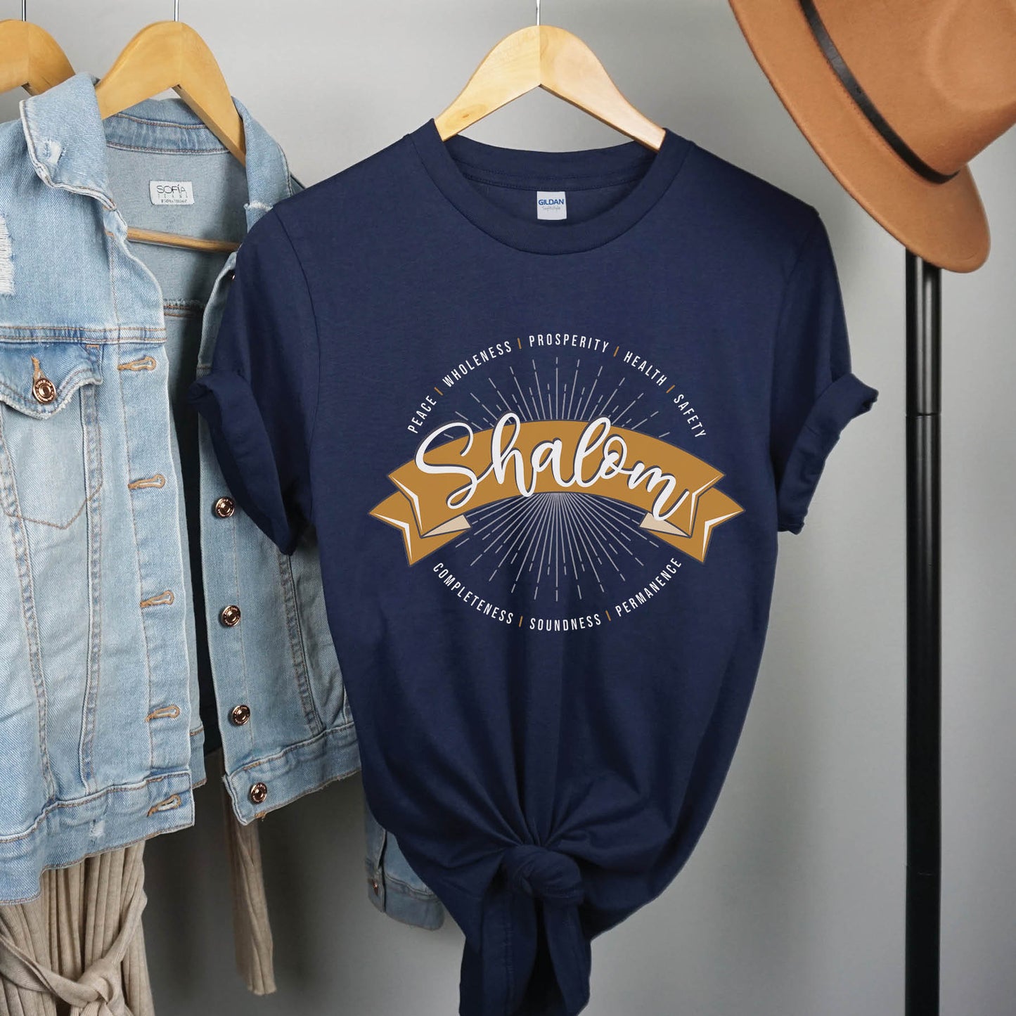 Soft navy blue faith-based Christian women's unisex t-shirt with a gold banner and sunburst design that says the Biblical Hebrew meaning of the word "SHALOM" - Peace, Completeness, Prosperity, Health, Safety, Wholeness, Soundness, and Permanence definition, makes a great mother's day gift for mom!