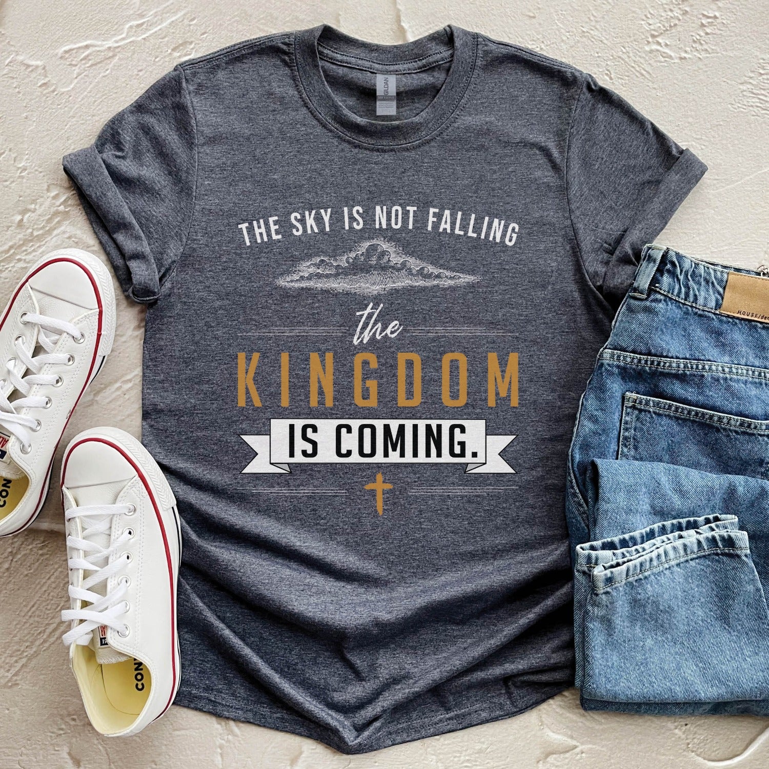 Heather dark gray unisex t-shirt with a Christian Kingdom of God through Jesus faith-based message that says, "The Sky Is Not Falling, The Kingdom is Coming" with bold font, vintage clouds, banner, and cross design in white and gold, created for bible study Men and Women believers, 2024 eclipse
