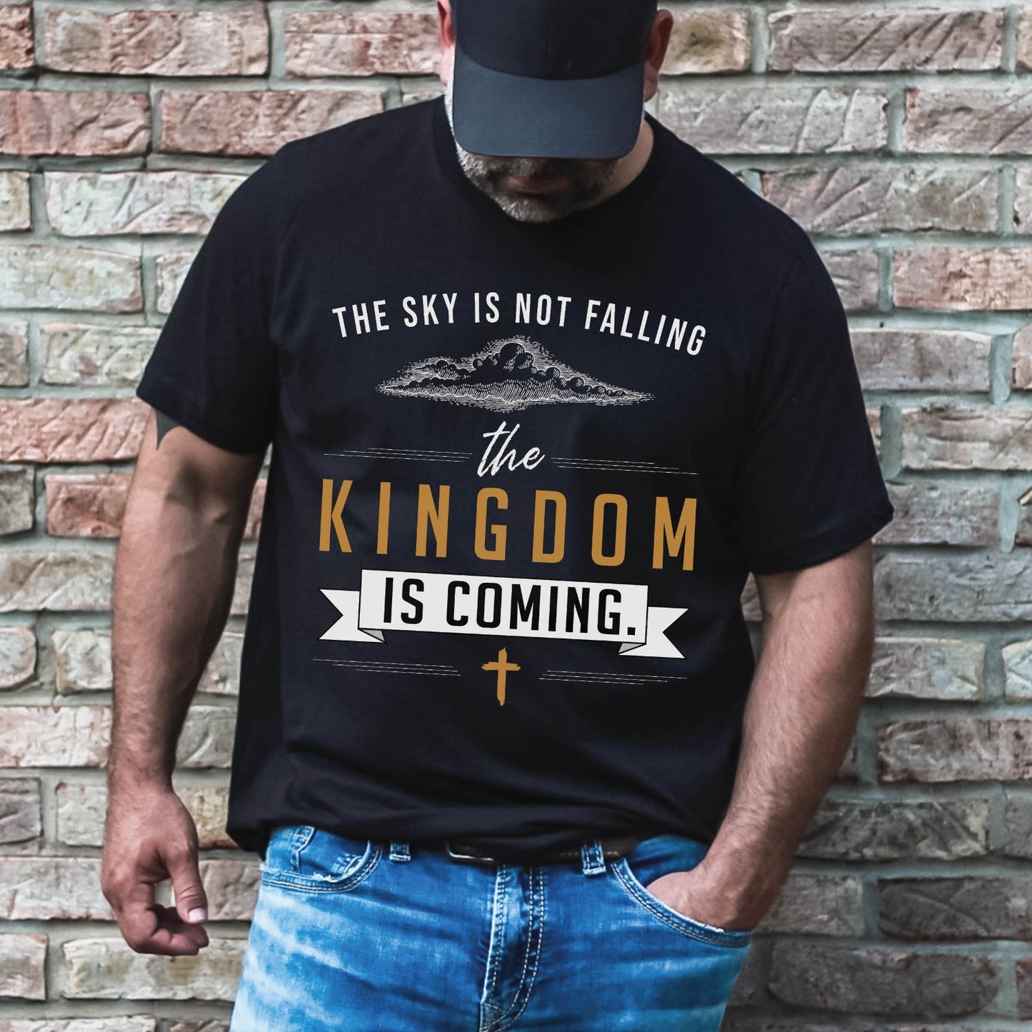 Bearded man wearing a black unisex t-shirt with a Christian Kingdom of God through Jesus faith-based message that says, "The Sky Is Not Falling, The Kingdom is Coming" with bold font, vintage clouds, banner, and cross design in white and gold, created for bible study Men and Women believers, 2024 eclipse