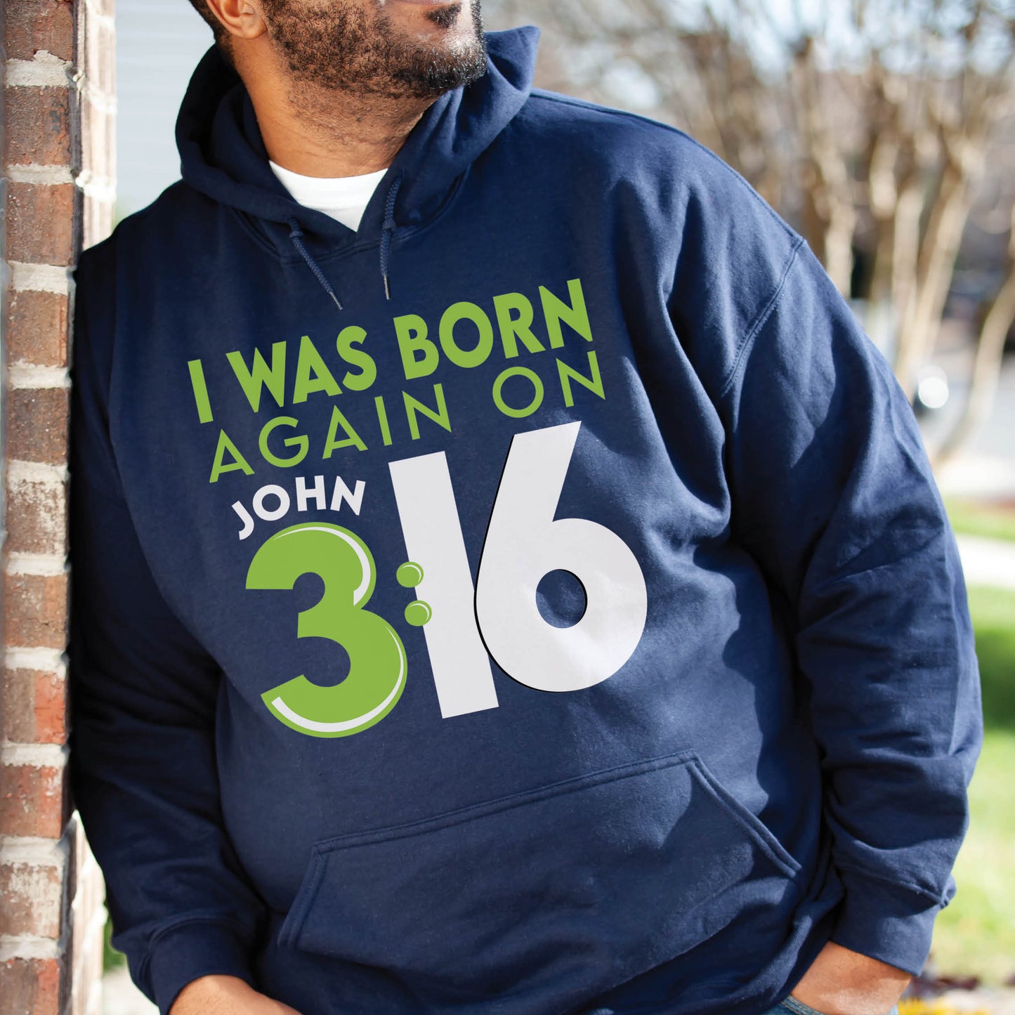 Black man wearing oversized navy blue Unisex Cozy Hoodie with Christian aesthetic bible verse message that says, "I Was Born Again On John 3:16" bible verse quote in lime green and white for men and women