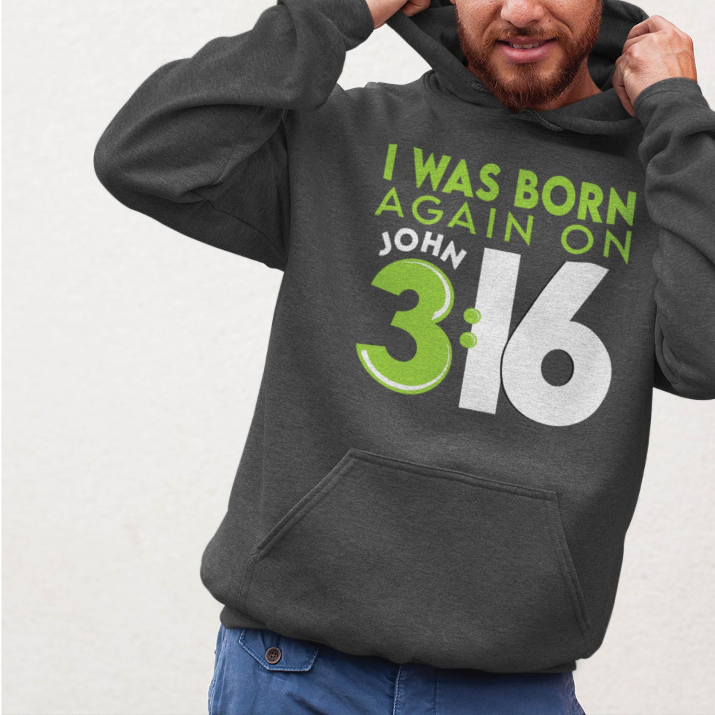 Bearded man wearing a heather dark gray Unisex Cozy Hoodie with Christian aesthetic bible verse message that says, "I Was Born Again On John 3:16" bible verse quote in lime green and white for men and women