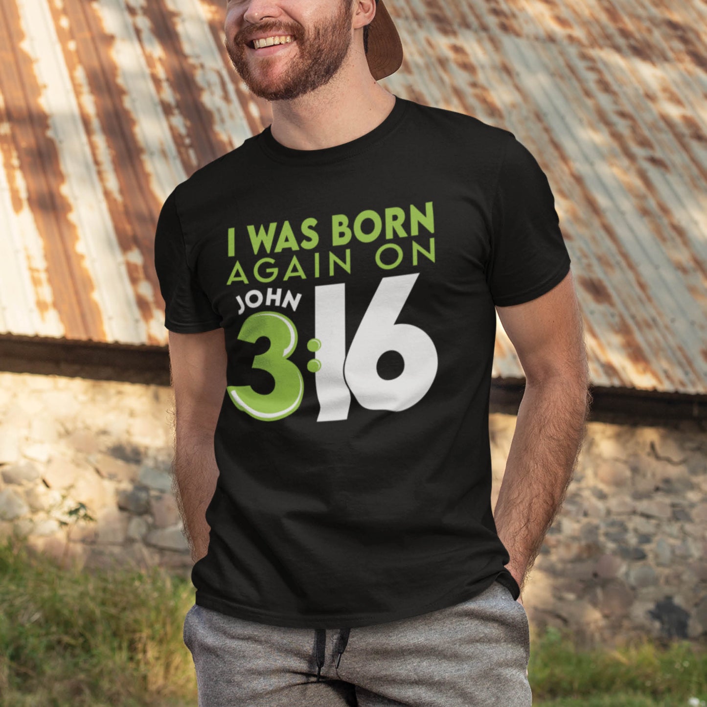 Trendy young bearded man wearing a Black Christian aesthetic unisex t-shirt with a play on words that says, I Was Born Again on John 3:16, bible verse scripture quote in lime green and white, designed for men and women