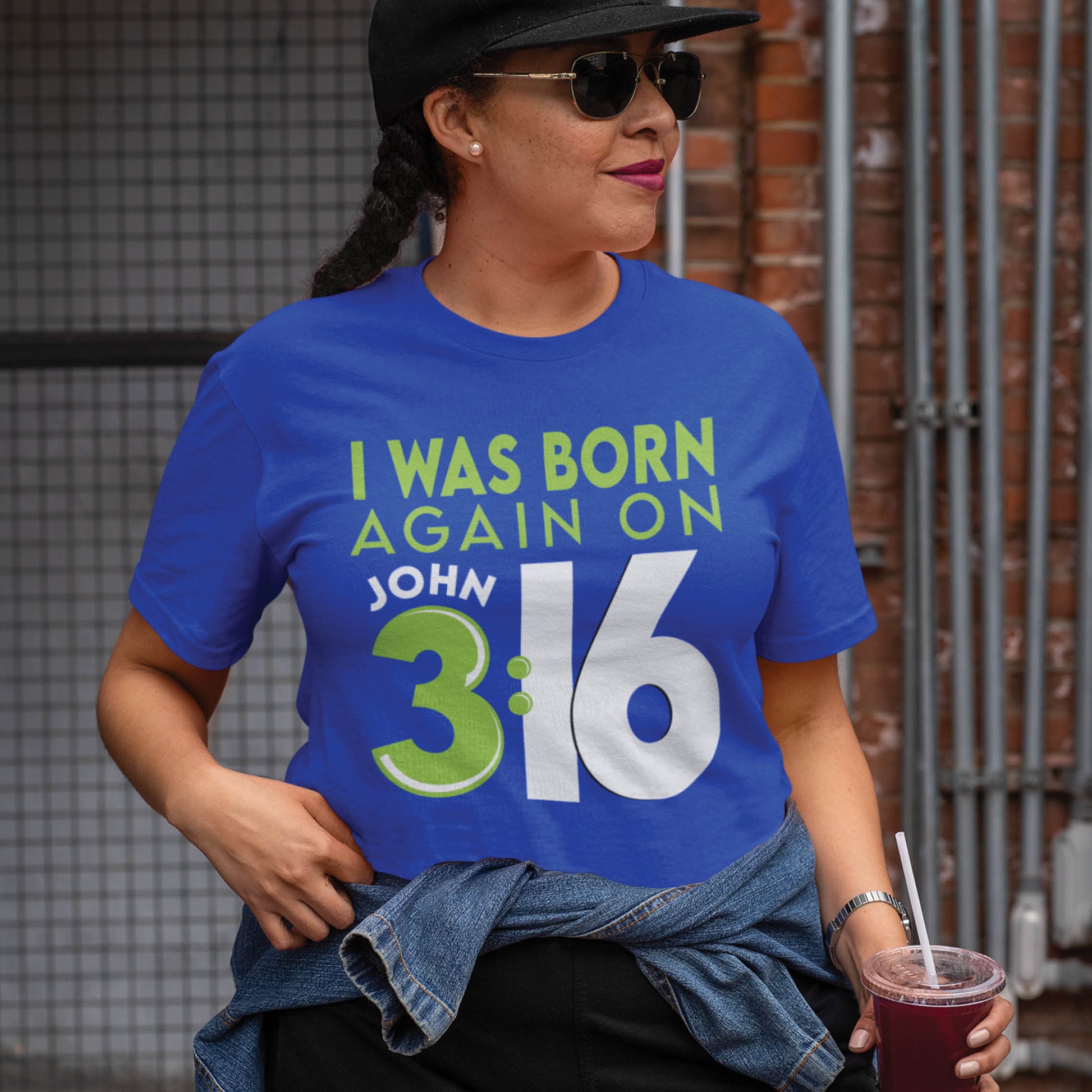 Black woman wearing a casual True Royal Blue color Christian aesthetic unisex t-shirt with a play on words that says, I Was Born Again on John 3:16, bible verse scripture quote in lime green and white, designed for men and women