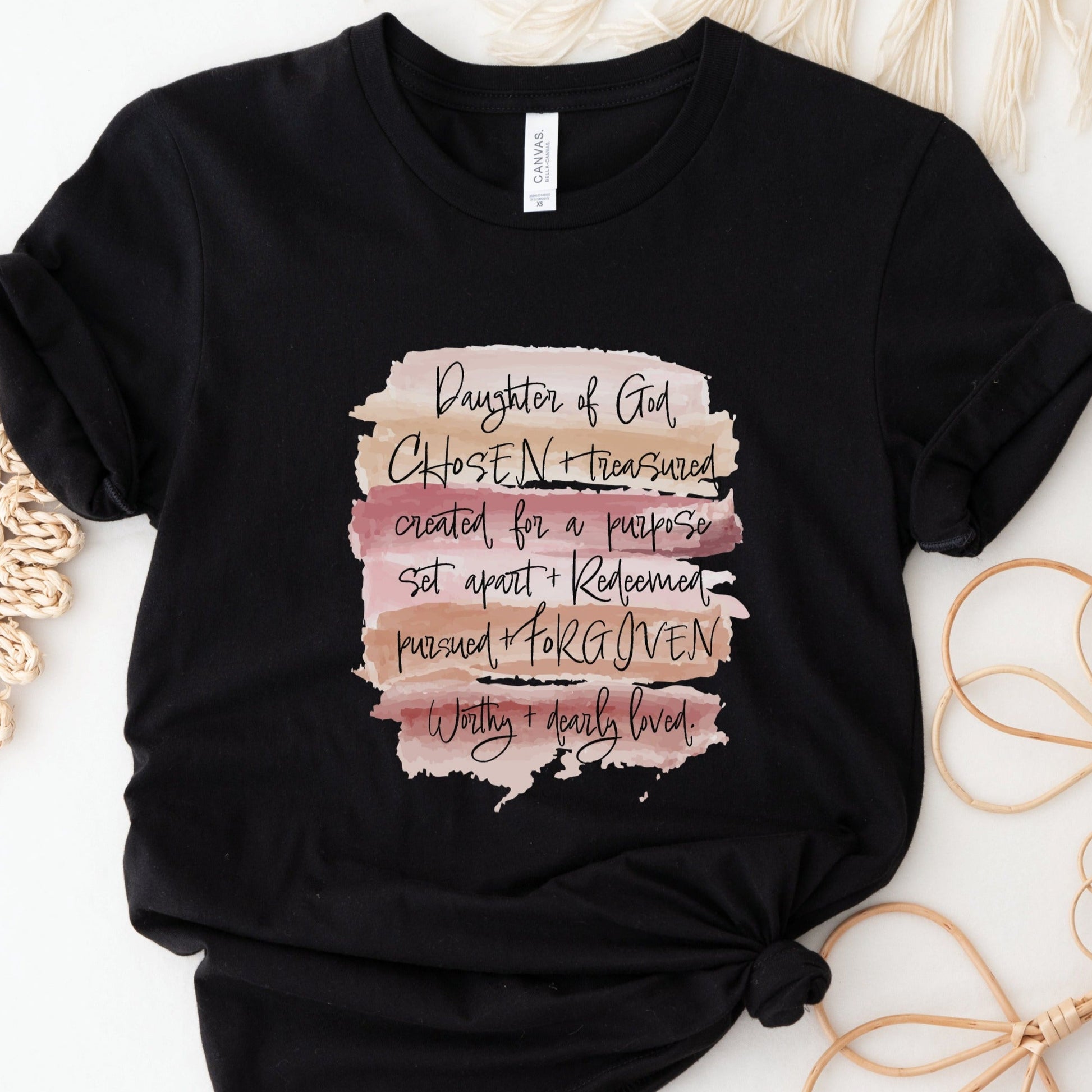 Daughter of God, Chosen, created for a purpose, redeemed, forgiven, worthy, loved, Christian woman aesthetic with neutral colors watercolor splash background printed on soft black unisex t-shirt for women
