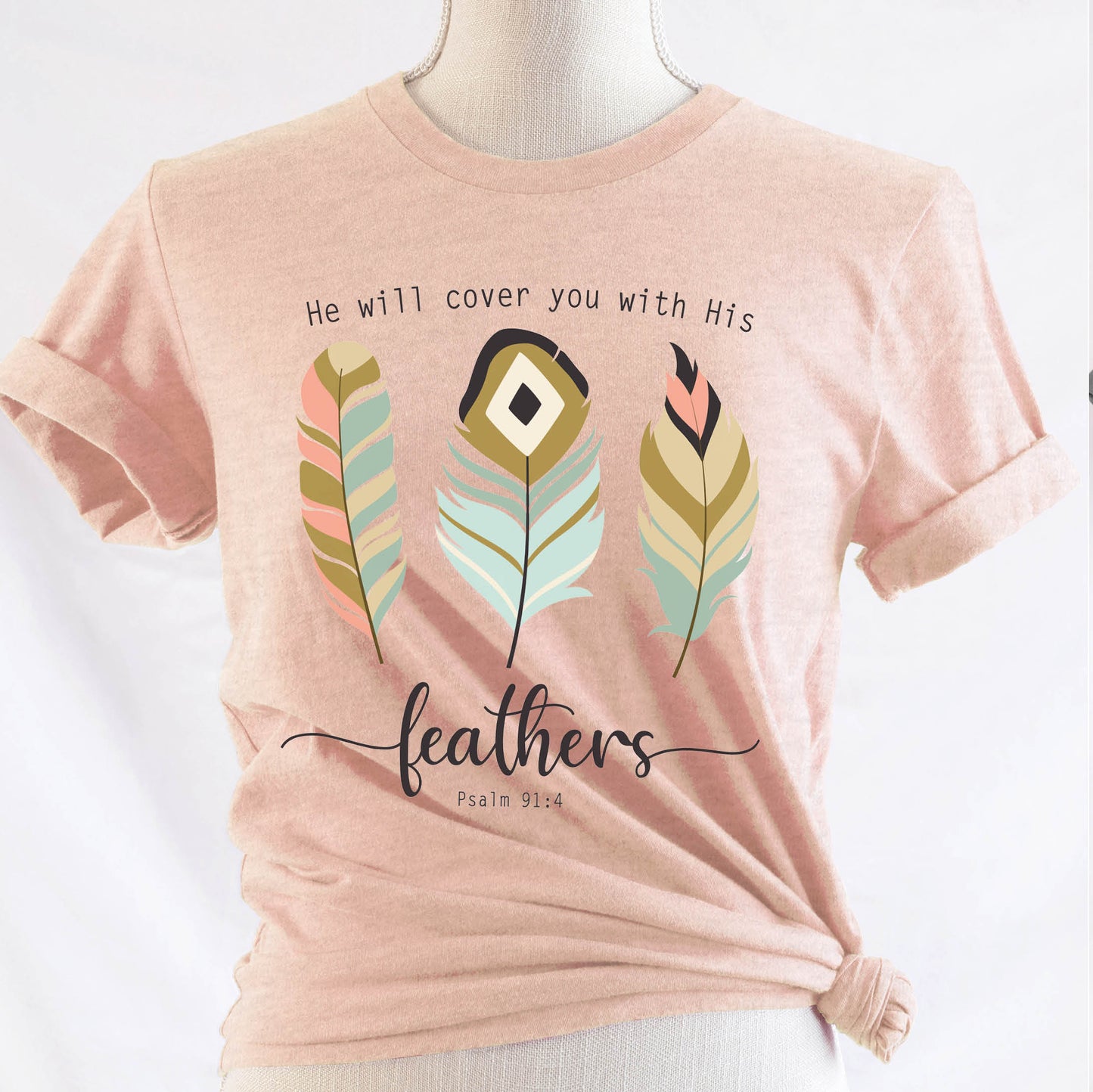 Psalm 91:4 "He Will Cover You With His Feathers" boho bible verse Christian woman aesthetic with teal peach and gold feathers printed on soft heather prism peach unisex t-shirt for women