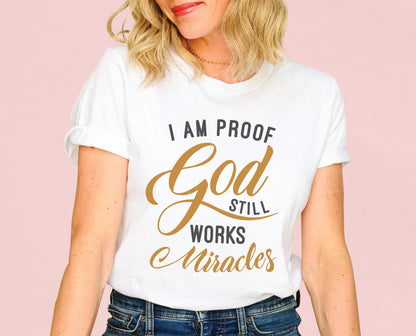 I am proof God still works miracles Christian aesthetic testimony design printed in charcoal and gold on white unisex t-shirt for women